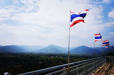 Flag on railing against mountain range against sky