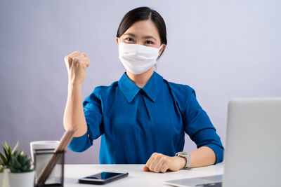 Portrait of young woman wearing mask on table