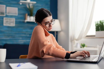 Woman using phone while sitting on table