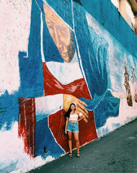 Full length of woman standing against graffiti wall