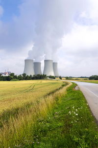 View of factory field against cloudy sky