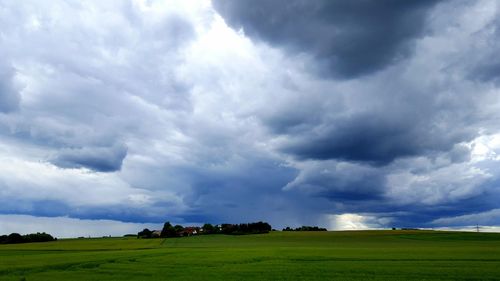 Scenic view of grassy field against cloudy sky