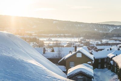 Snow covered houses by buildings against sky