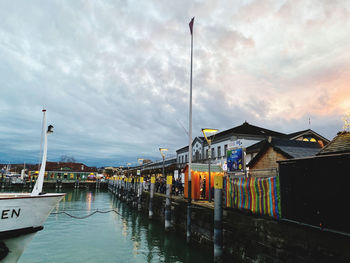 Fishing boats moored on river by buildings against sky