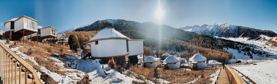 Panoramic view of buildings and snowcapped mountains against sky