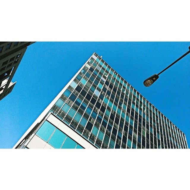 low angle view, building exterior, architecture, built structure, modern, office building, blue, skyscraper, city, tall - high, clear sky, tower, building, glass - material, sky, reflection, tall, street light, day, outdoors