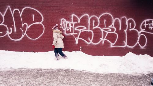 Person walking on sidewalk against brick wall