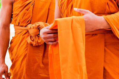 Midsection of man holding orange while standing in temple