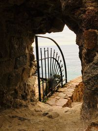 View of gate on rock formation against sea