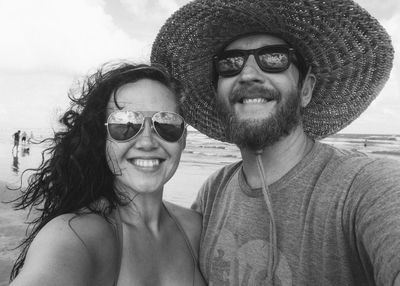 Portrait of smiling couple wearing sunglasses at beach