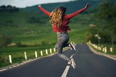 Young woman jumping on road