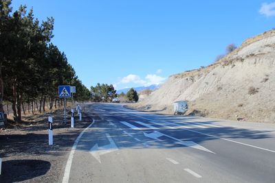 Road by trees against blue sky