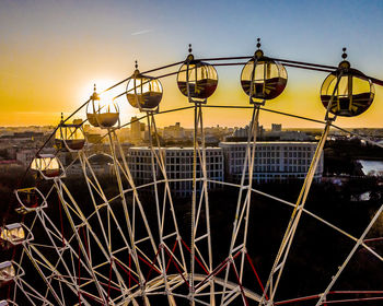 Ferris wheel by sea against sky at sunset