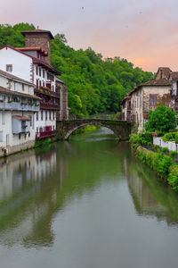 Arch bridge over river by buildings against sky