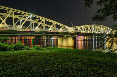 Bridge over river against sky at night