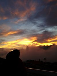 Rear view of silhouette man against orange sunset sky