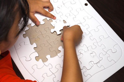 High angle view of girl solving jigsaw puzzle on table