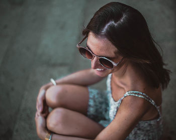 Young woman looking away while sitting on wall