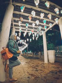 Woman standing on illuminated footpath at night