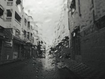 Wet street amidst buildings in city