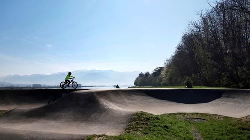 Child riding bicycle on pumptrack against sky