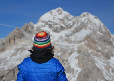 Rear view of man standing against snowcapped mountain