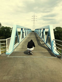 Man on bridge against sky