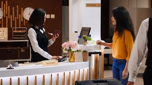 Side view of young woman using mobile phone while standing in cafe