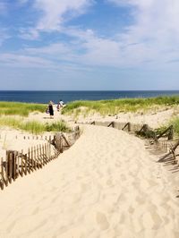 View of sandy beach against cloudy sky on sunny day