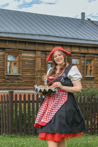 Portrait of young woman standing against fence