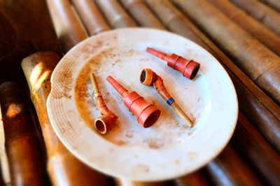 High angle view of smoking pipes in plate on bamboos