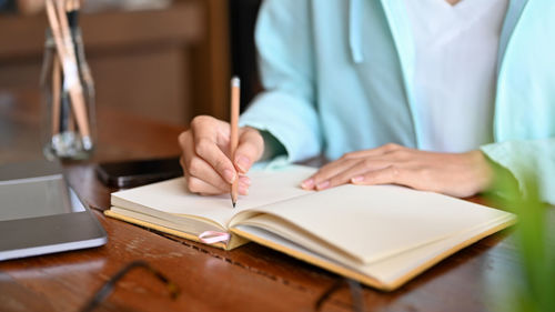 Midsection of doctor writing in book at clinic
