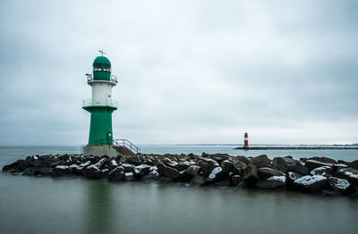 Lighthouses in sea against cloudy sky