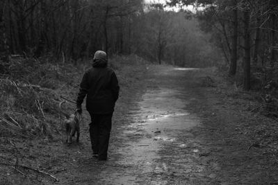 Full length of woman with dog walking in forest