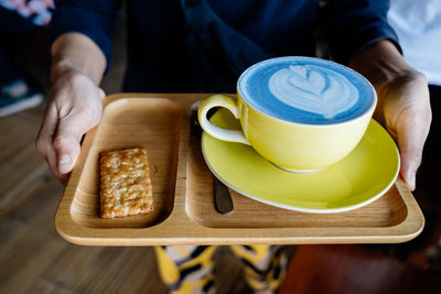 Midsection of person holding coffee cup on table