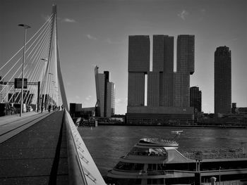 Modern buildings by river against sky in city