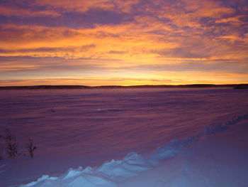 Scenic view of snow covered land against sky during sunset