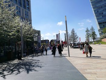 People walking on footpath amidst buildings in city