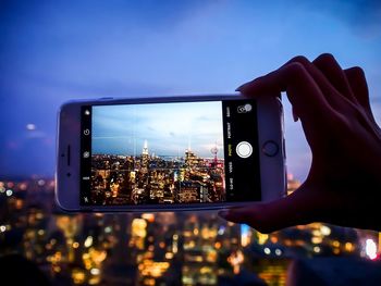 Low angle view of hand using mobile phone against sky