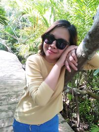 Portrait of woman with sunglasses standing against trees