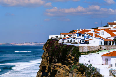 Houses by sea against sky