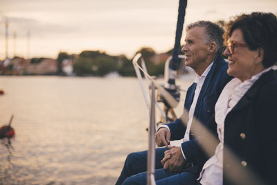 Side view of senior man and woman holding hands while traveling in yacht