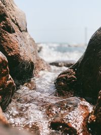 Close-up of rocks in sea against clear sky