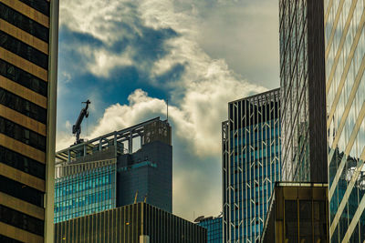 Low angle view of skyscrapers against cloudy sky
