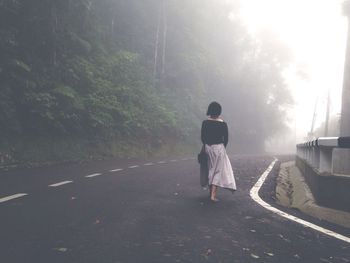 Rear view of woman walking on road