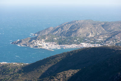 Aerial view of sea by mountain against sky