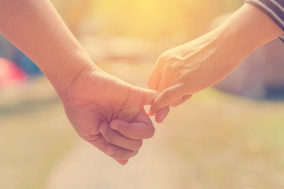 Close-up of friends taking pinky promise outdoors