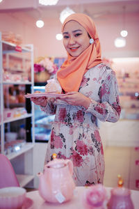 Portrait of a smiling young woman standing in store