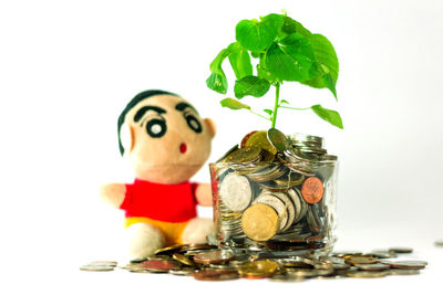 Close-up of coins in jar against white background