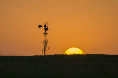 Silhouette crane on field against orange sky